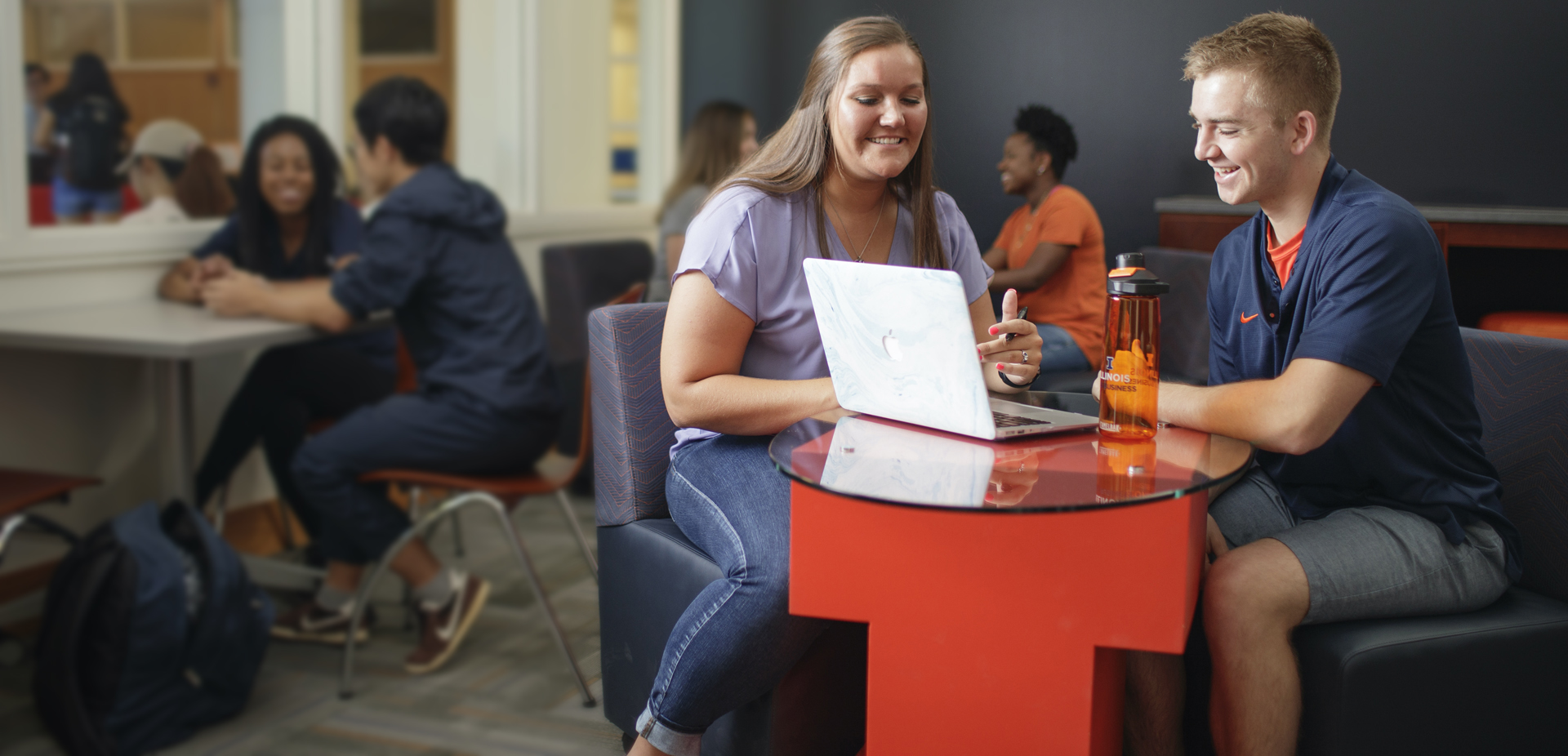 Gies Homepage students sitting at table looking at laptop